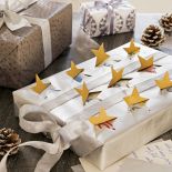 Żółty lub złoty papier odwróć na drugą stronę, ponacinaj gwiazdki, a potem opakuj prezent i otwórz gwiezdne okienka .