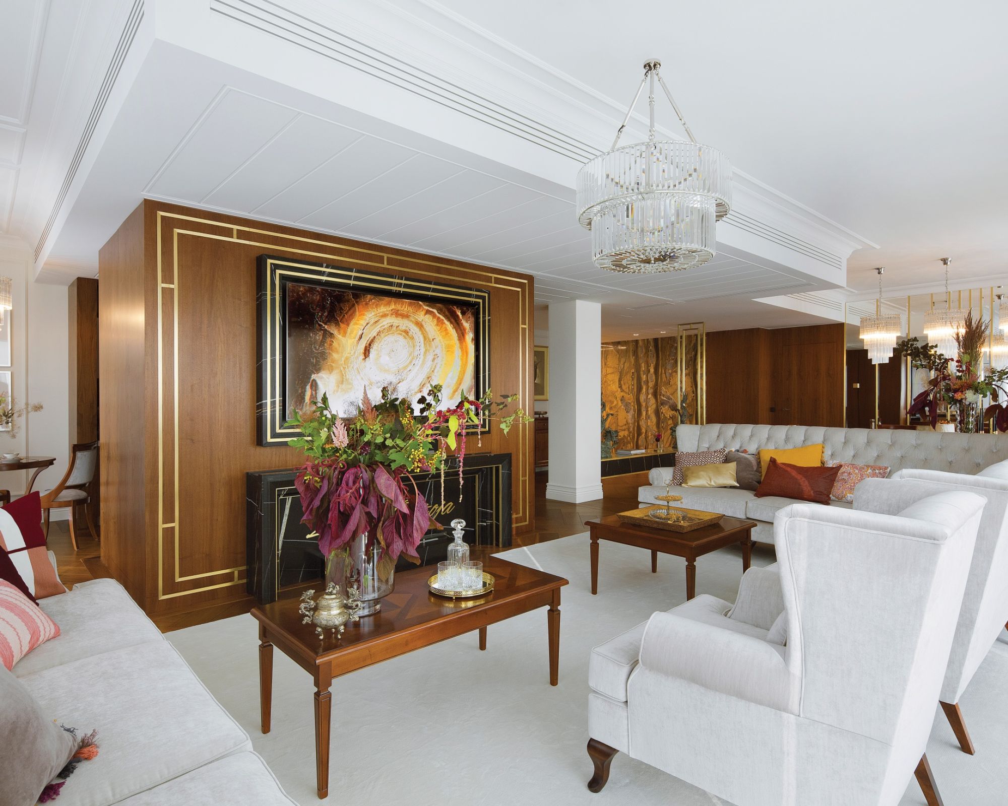 Do orzechowego drewna na podłodze i ścianach architekci wybrali kremowe sofy i dywany, dzięki czemu salon jest lżejszy i