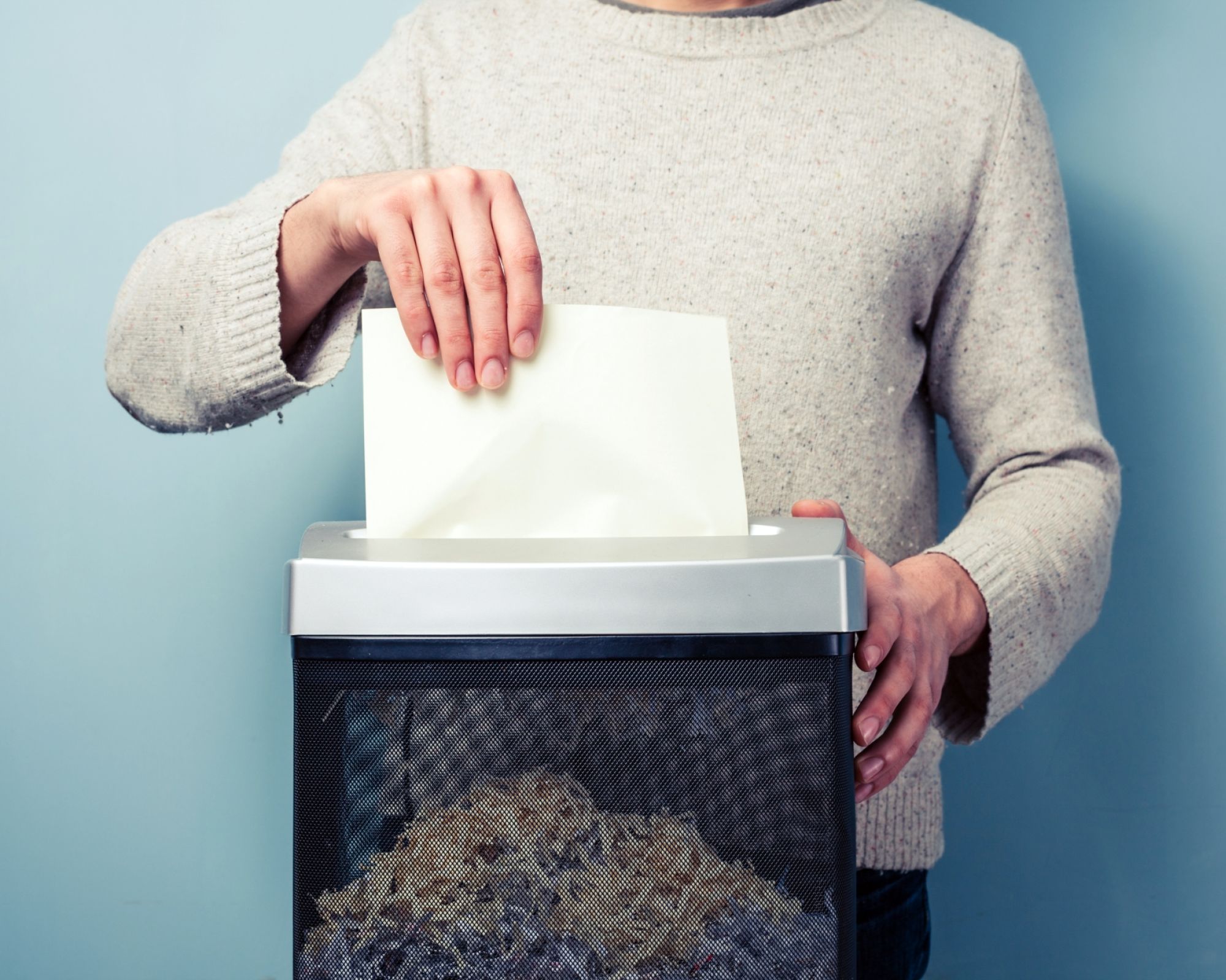 kobieta wkłada kartki papieru do niszczarki dokumentów