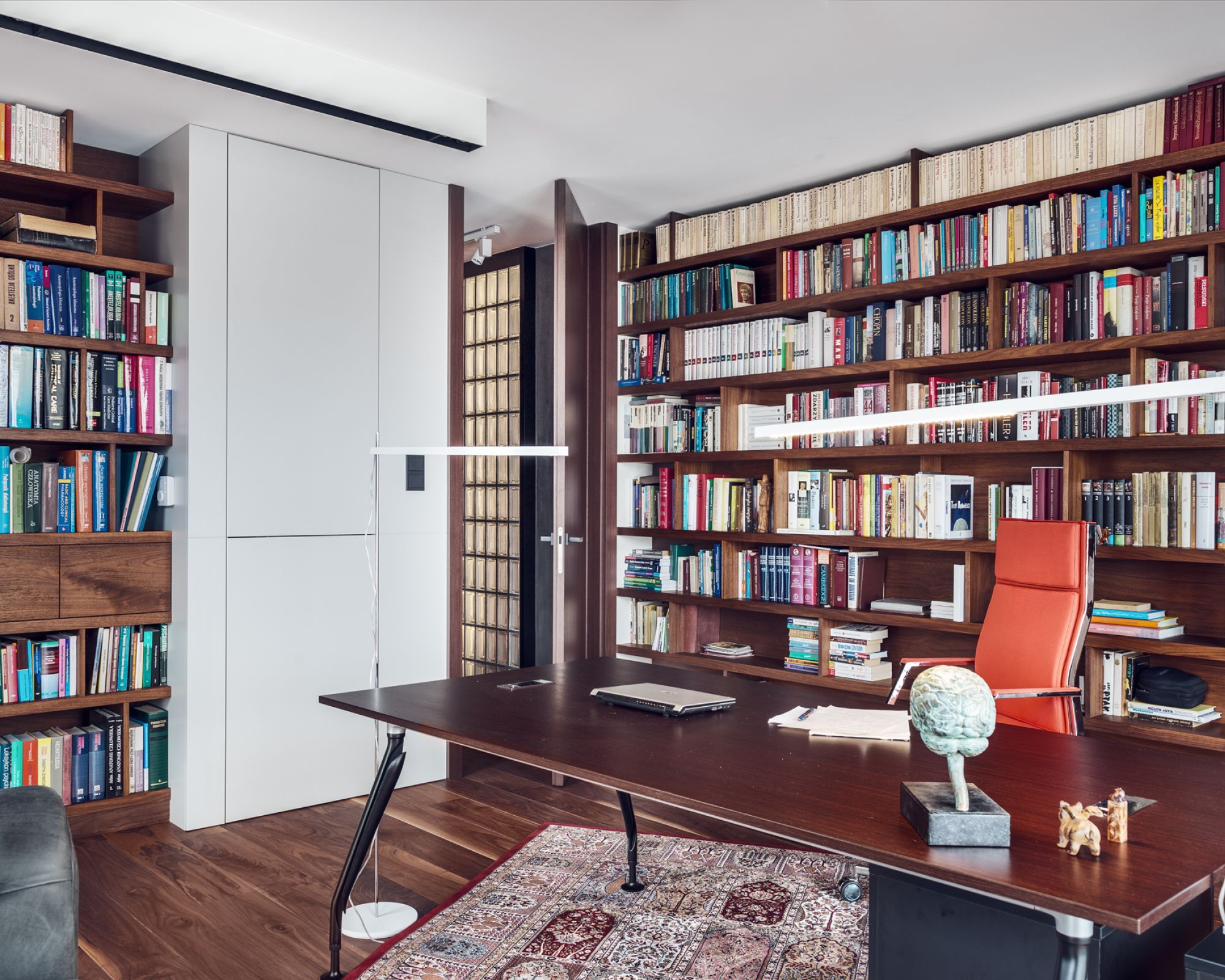 Klasycznego charakteru nadają ciężkie, czarne żaluzje, sofa w stylu chesterfield oraz klasyczny perski dywan.