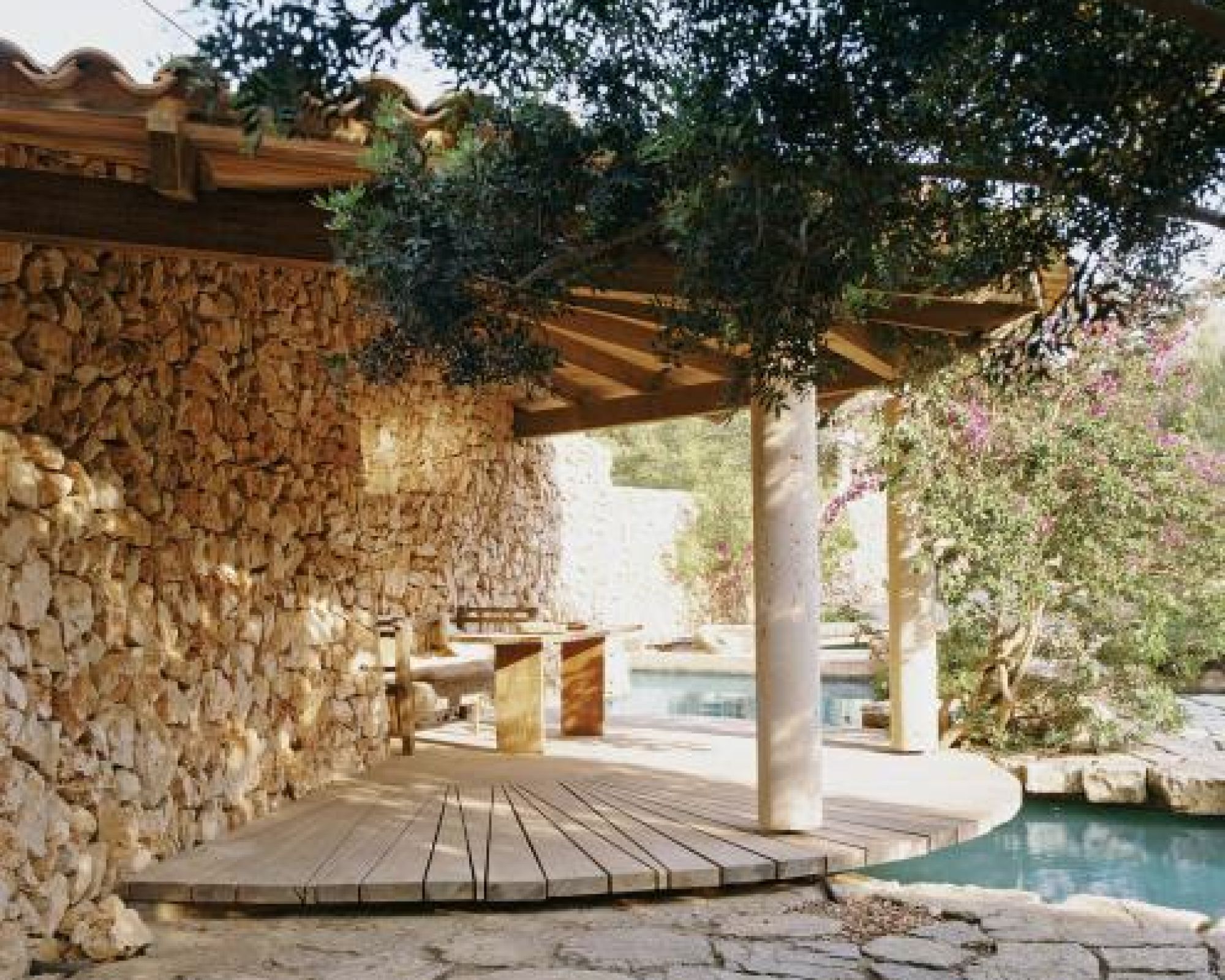 Na tarasie dominuje jasny kamień i surowe drewno.