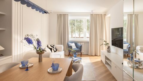 Jasny salon z jadalnią, lustrzaną szafą i designerską lampą w odcieniu burzowego błękitu
