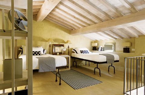 Surowe, drewniane stoły i składane krzesła inspirowane angielskimi meblami kolonialnymi solidne łoża z baldachimem obok