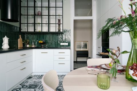 biała kuchnia z czarnym blatem i zielonymi płytkami