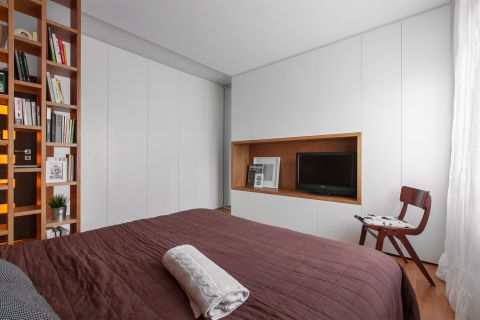 Dzięki drewnianemu regałowi, podłodze oraz wnęce sypialnia stała się bardziej przytulna.