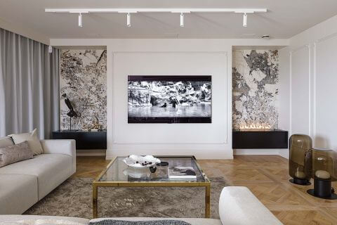 telewizor w salonie obramowany sztukaterią i biokominkiem w kamiennej obudowie