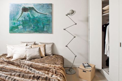 Jedyny kolorowy akcent w beżowo-szarej sypialni to obraz Mariusza Andryszczyka. Obok łóżka stoi kultowa lampa