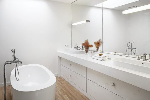 Lustra optycznie powiększają łazienkę. Na podłodze drewno.