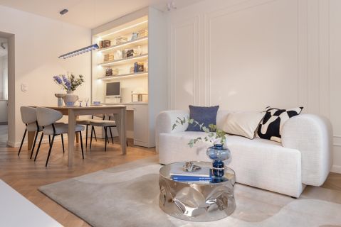 Jasny salon z jadalnią, lustrzanym stolikiem kawowym i dodatkami w odcieniu błękitu w mieszkaniu 60 m2 w bloku