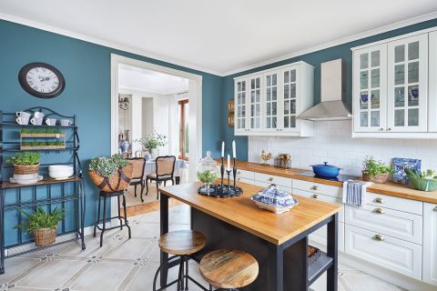 niebieska kuchnia z białymi szafkami i drewnianym blatem