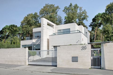 Nowoczesna bryła pośród drzew. Dom nowoczesny z trawertynami i agatami