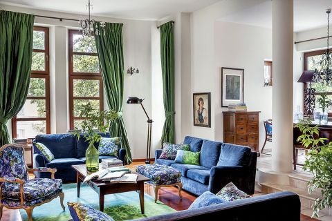 otwarta przestrzeń, wielkie okna. Światło wpada do salonu z czterech stron i aż lśni na tkaninach.