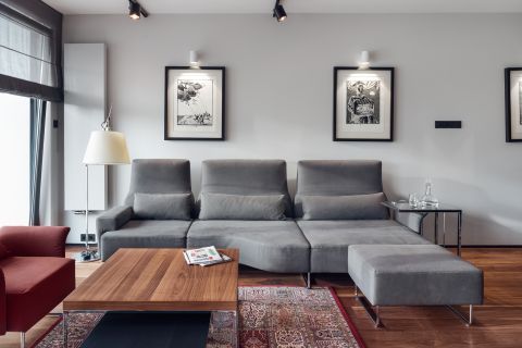 Salon to wielkomiejski eklektyzm: nowoczesna kanapa, modernistyczny stolik, orientalny dywan.