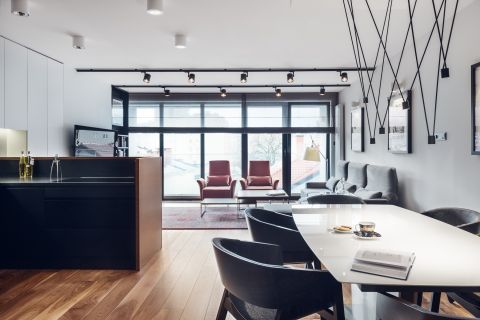 Salon umeblowano w proste meble. Pomieszczenie doświetla naturalne światło wpadające przez loftowe okna.