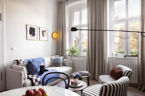 sofa i fotel w pasy w eklektycznym salonie w kamienicy