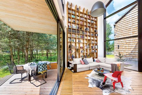 Z salonu jest wyjście na taras. Nowoczesny dom kryty gontem