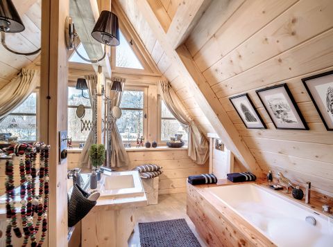 Lustrzana ściana powiększa łazienkę. Do tego dwuosobowa wanna obłożona drewnem i kabina prysznicowa firmy New Trendy.