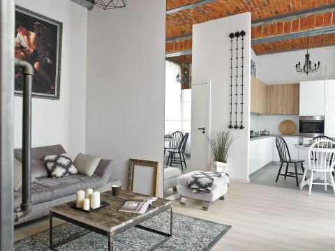 Do czerwieni cegły pasują stonowane dodatki. Szary pled, poduszki we wzór marokańskiej koniczyny i te