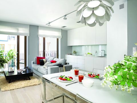 Szafki kuchenne zrobione na zamówienie z lakierowanego MDF-u. Sofa marki Dublo, dywan, szare poduchy i koc - Belbazaar.