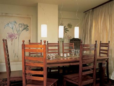 w jadalni króluje prostota - nad surowym stolem w kolonialnym stylu wiszą minimalistyczne lampy.
