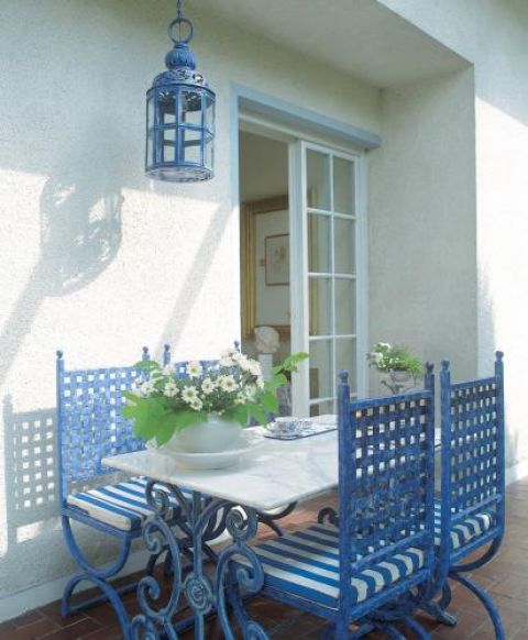 Na tarasie stoją niebieskie krzesła i stół.