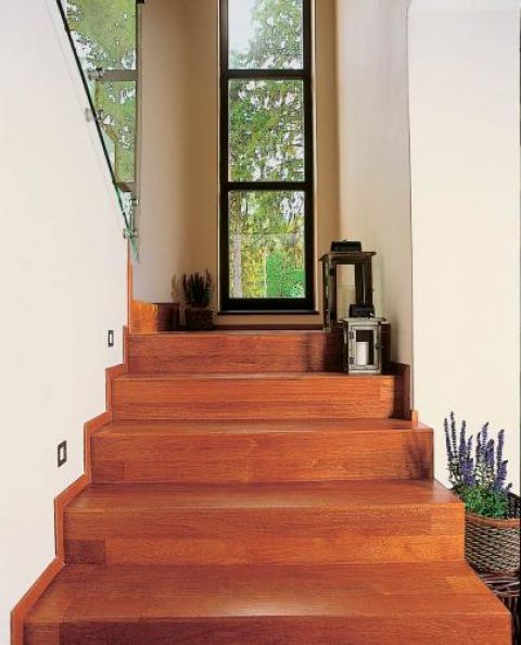 Schody na piętro wyłożone egzotycznym drewnem.