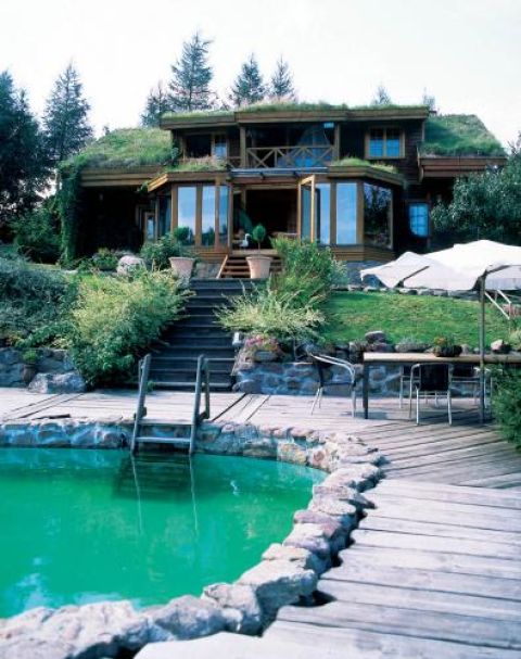 Tuż obok domu jest basen otoczony kamieniami i drewnianym chodnikiem.