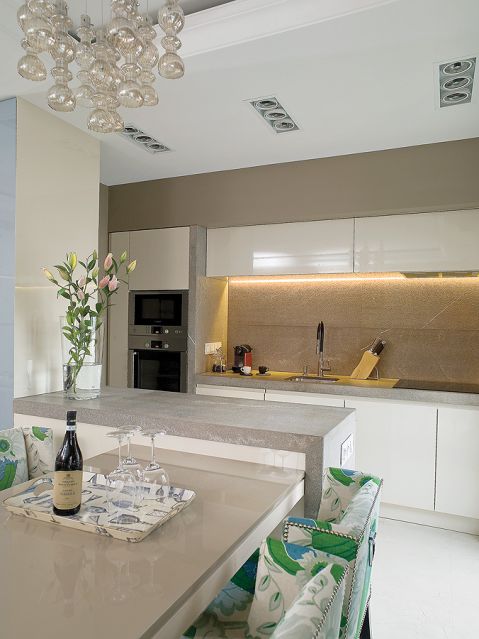 Chłodny kamień i fronty na wysoki połysk ocieplaja krzesła obite lnem marki Christopher Farr.