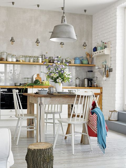 W jadalni drewniany okrągły stół i białe krzesła.