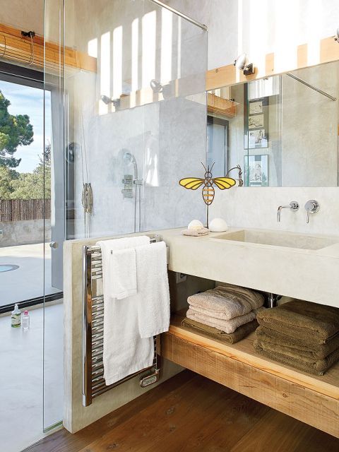 W łazience ciekawe zestawienie betonowych, szarych ścian z ciepłym drewnem, z którego wykonano półkę pod umywalką.