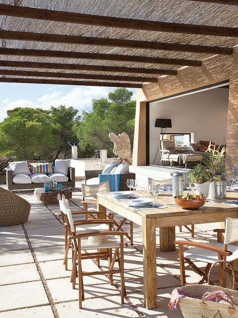 Taras z jadalnią: drewniany stół, krzesła, a obok wygodne kanapy.