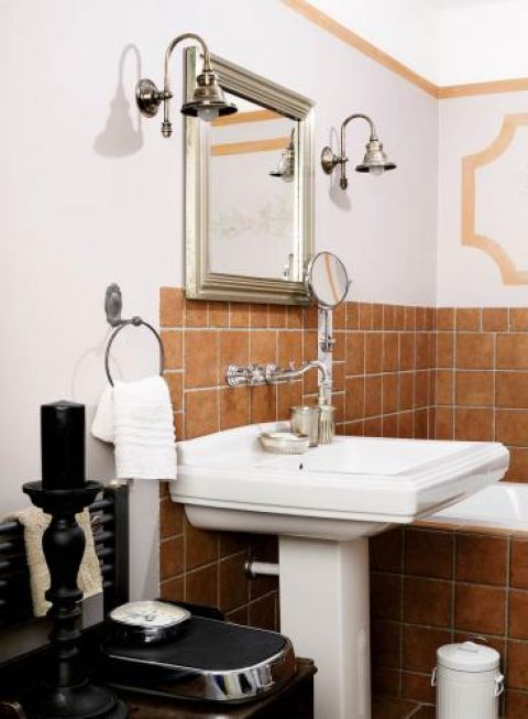 Metalowa rama lustra i ozdobne kinkiety.