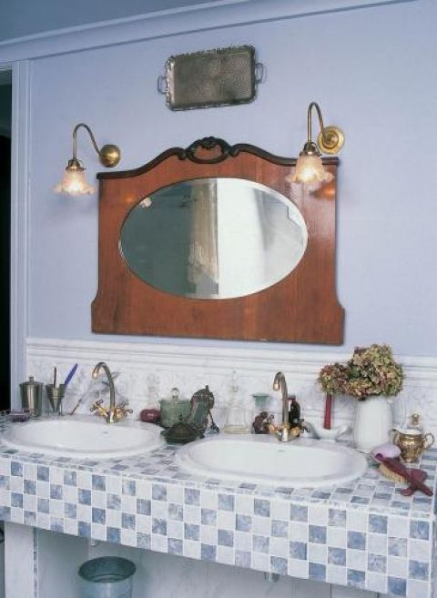 Nad umywalkami wisi lustro w drewnianej ramie.