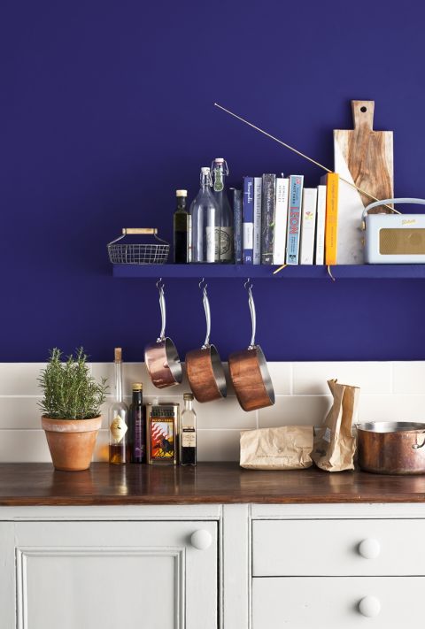 Granatowa ściana i białe szafki w kuchni