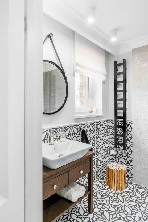 W gościnnej łazience na dole czarno-biała klasyka. Ale bez nudy: grzejnik przypomina drabinę, a lustro ma pasek jak damska