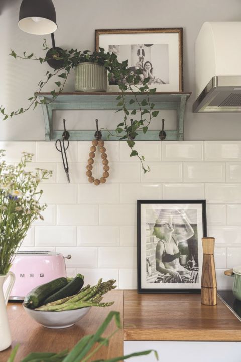 biała kuchnia z drewnianym blatem i zielonymi akcentami