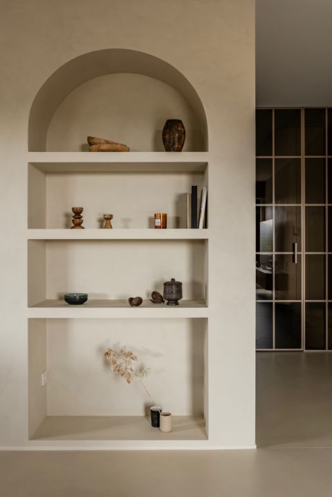 wnęka w kształcie łuku z półkami na książki i dekoracyjne przedmioty
