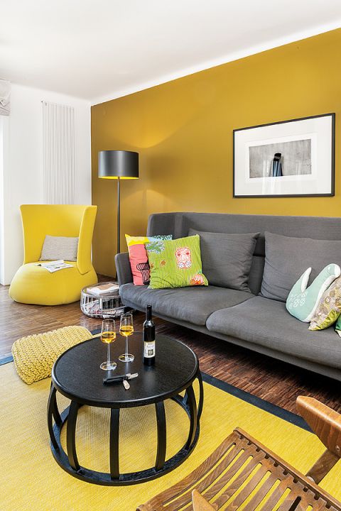 Ciepły palisandrowy parkiet i miodowa ściana. Do tego dizajnerskie meble. Sofa z Vitry, lampa marki