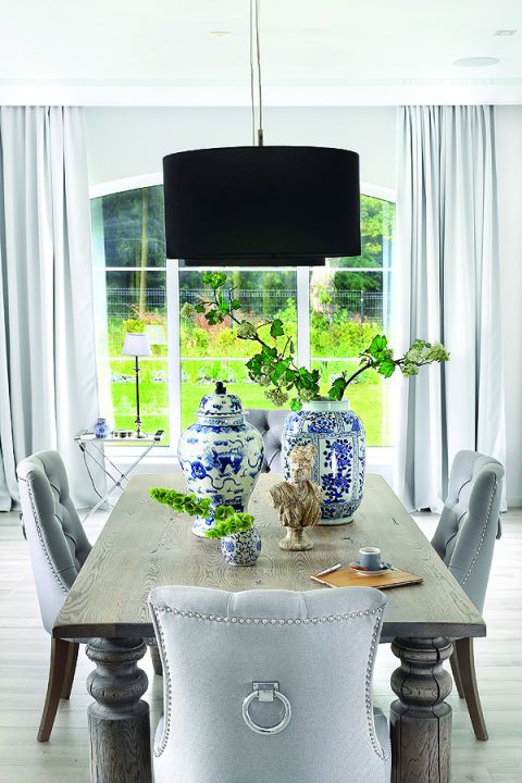 Do dużego masywnego stołu od firmy Jadik pasują fotele ze srebrnymi uchwytami z Decolor i kobaltowe wazony od Casa Mia.