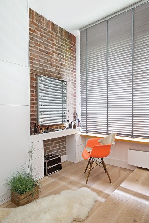 Sypialnia z ceglanymi ścianami i pomarańczowymi detalami.