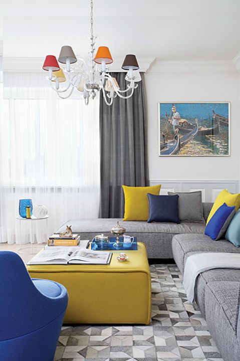 Granatowy fotel jest z 3F Studio. Żółty puf, białe stoliki, poduchy i dywan z kawałków skóry przyjechały z BoConcept.