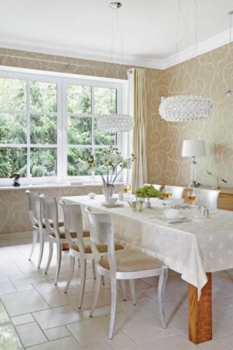 Harmonijnie, choć nie nudno. Kryształowe, eliptyczne lampy firmy Foscarini, kolonialny stół i klasyczne, srebrne krzesła.