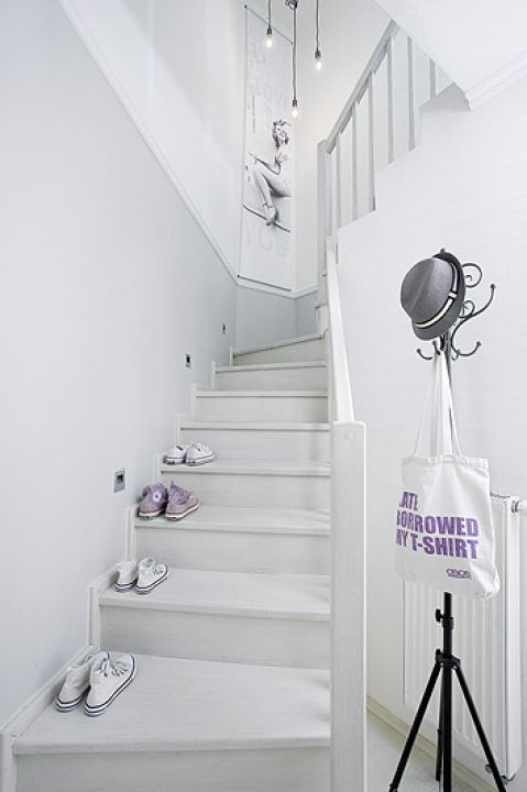 Jasno urządzone wnętrze, z kominkiem, ogromnymi oknami i drewnianym tarasem.