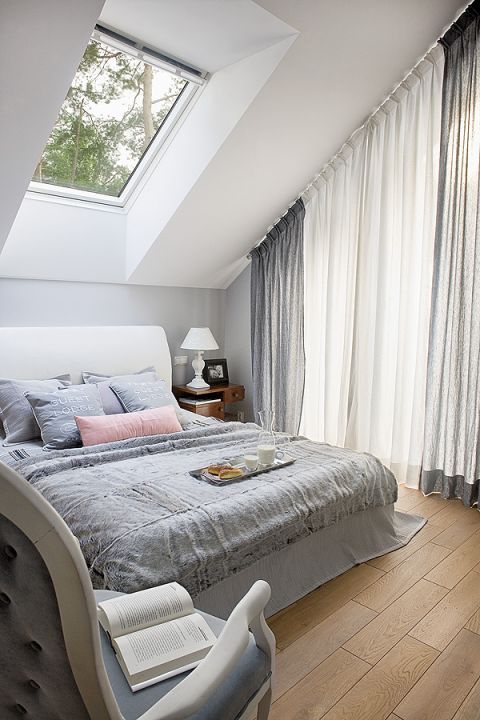 Kameralna sypialnia pod skosami z widokiem na las. Futro i poduszki to BBHome.