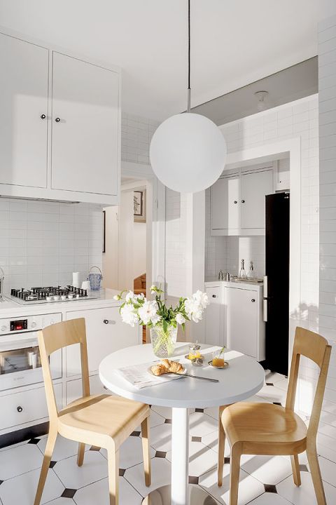 Kuchnia urządzona na biało - piękne kafle na ścianie i płytki na podłodze - w charakterystycznym dla międzywojnia kształcie i rozmiarze.