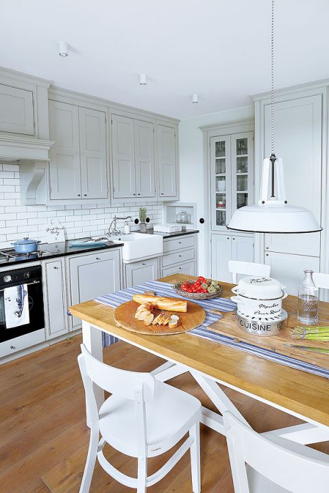 Kuchnia urządzona na biało z drewnianymi elementami.