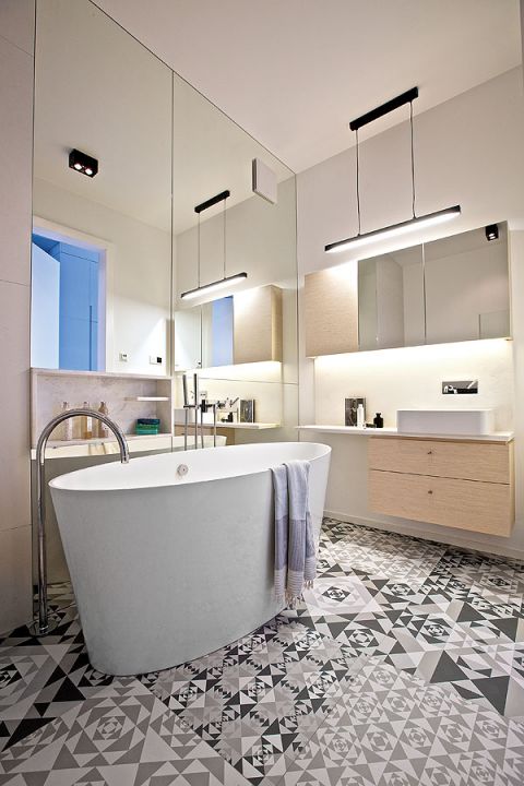 Łazienka kusi wolno stojącą wanną z luksusowymi bateriami Zucchetti i lustrami od podłogi po sufit.