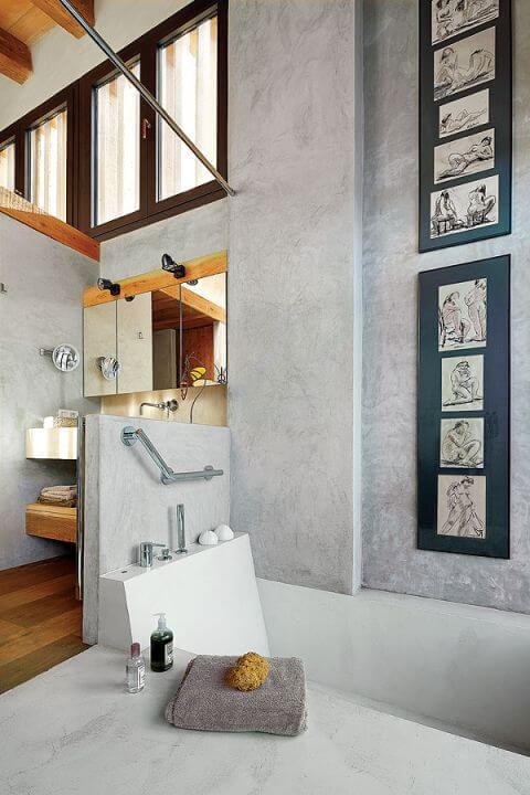 Nawet w łazience na ścianie wisi sztuka: do betonowych ścian pasują grafiki oprawione w antyramę.