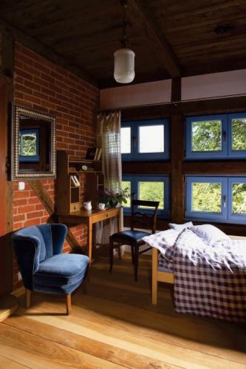 Niebieskie ramy okienne kontrastują z ceglanym murem.