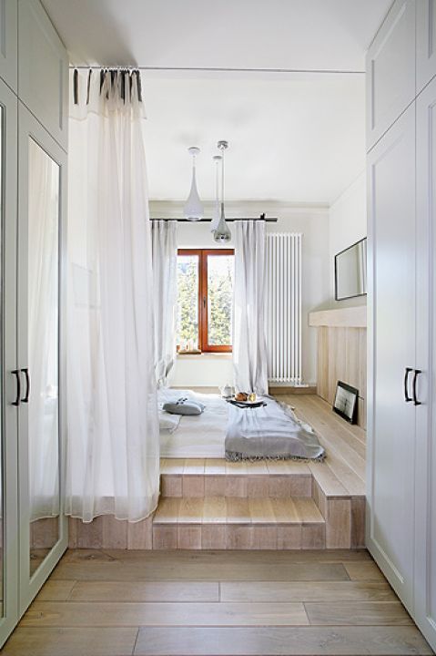 Wąskim przejściem mija się zabudowane szafy, by za chwilę trafić na drewniany podest, na którym leży materac.